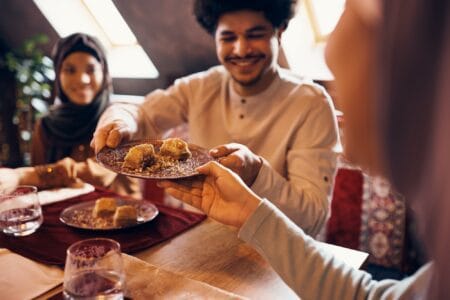 Close-up of Islamic family eating baklava at dining table at home.