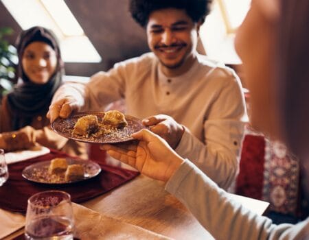 Close-up of Islamic family eating baklava at dining table at home.