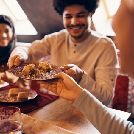Feqah: Ilmu Hukum Syariah Islam Close-up of Islamic family eating baklava at dining table at home.