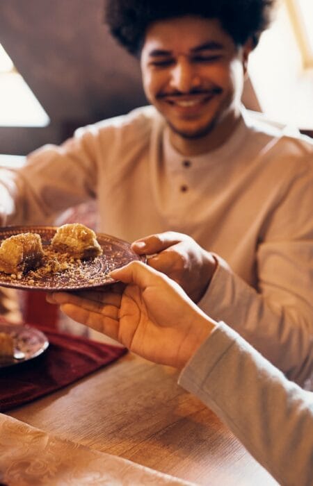 Feqah: Ilmu Hukum Syariah Islam Close-up of Islamic family eating baklava at dining table at home.