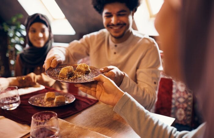 Close-up of Islamic family eating baklava at dining table at home.