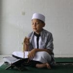 Muslim boy praying using prayer beads