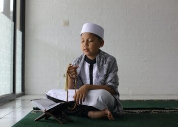 Muslim boy praying using prayer beads