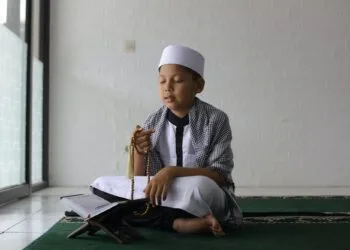 Muslim boy praying using prayer beads