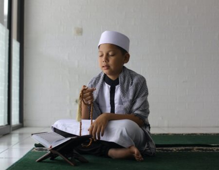 Muslim boy praying using prayer beads