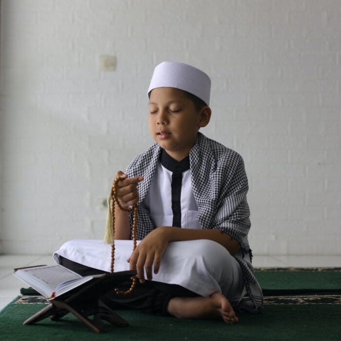 Muslim boy praying using prayer beads