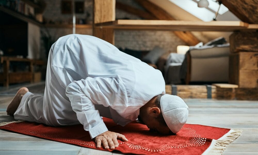 Solat: Tiang Agama Middle Eastern man performing ritual prayer on the floor at home.